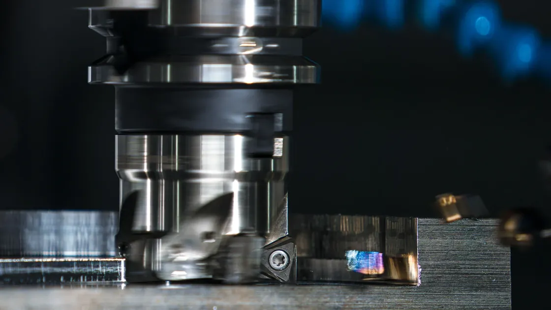 A precision milling tool cutting a metal workpiece inside a machine shop.