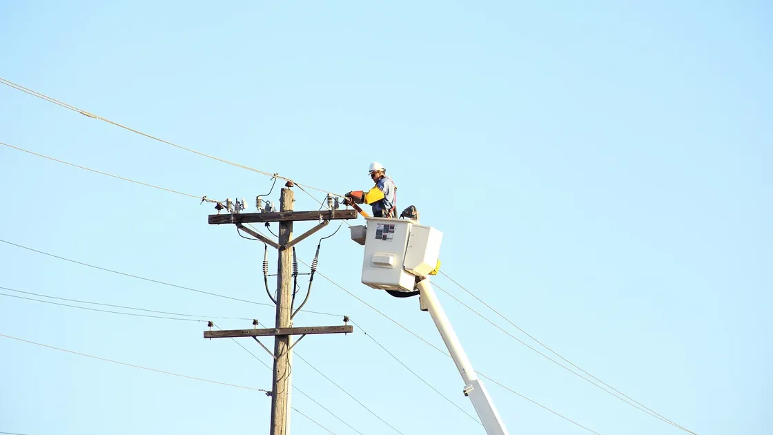 A lineworker in an elevated bucket servicing overhead power lines.