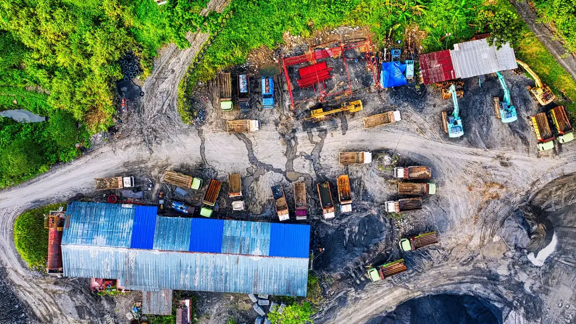 Overhead view of dump trucks, excavators and haul roads in a mining yard.