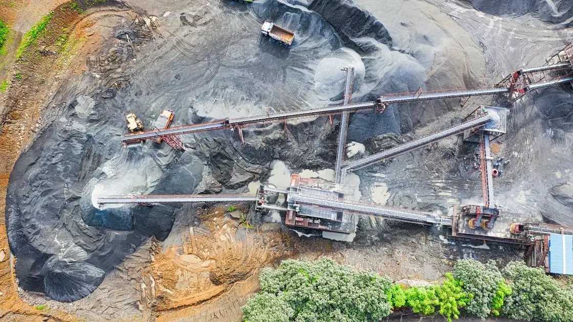 Aerial view of gray aggregate stockpiles connected by conveyor belts.