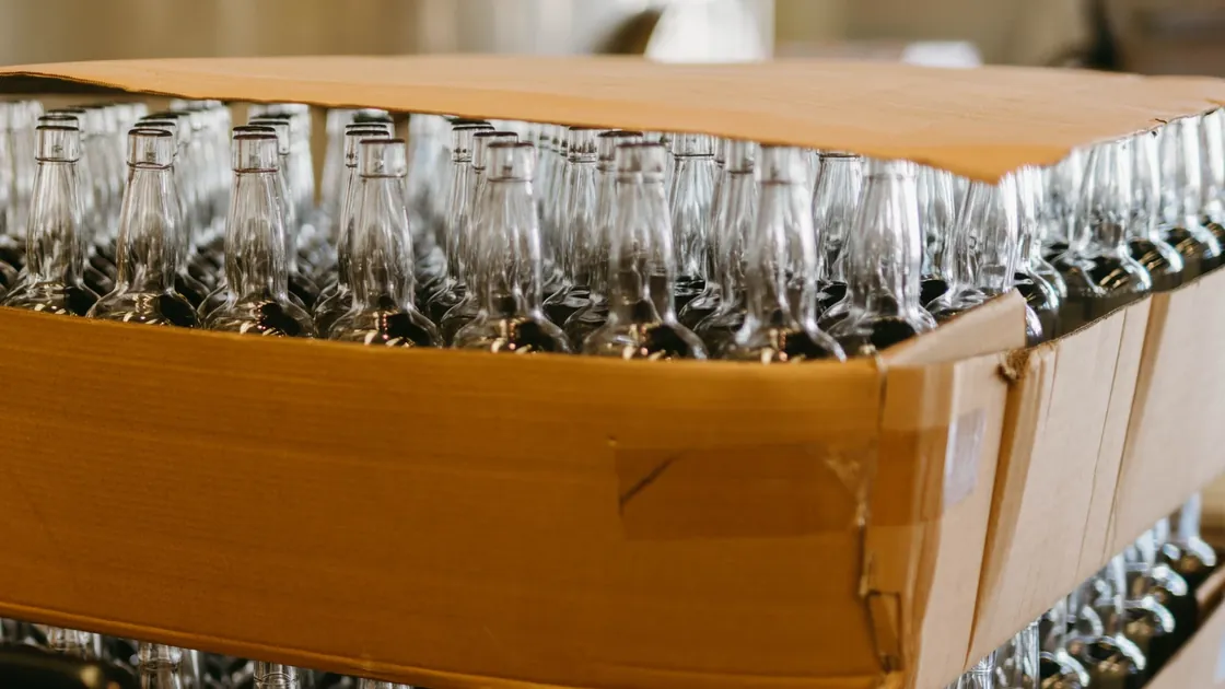 Rows of empty glass beverage bottles stacked in cardboard packaging.
