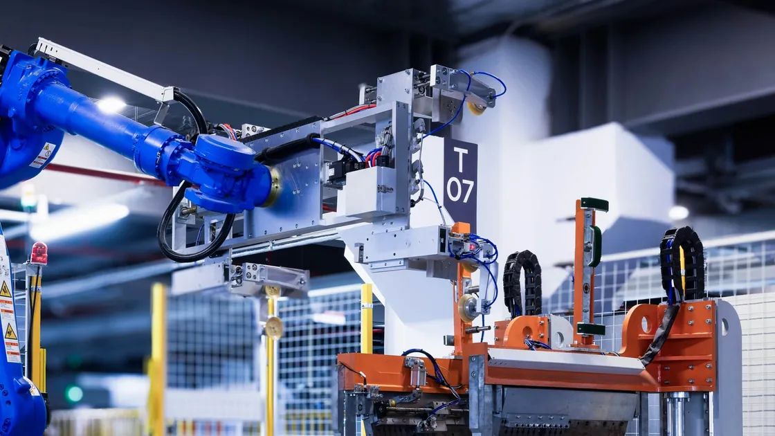 Close view of a robot wrist and panel-handling fixture at an assembly station.